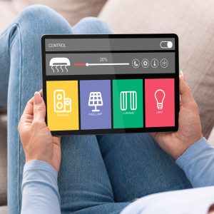 Smart home, saving electricity, controlling level of lighting, ventilation sound and climat. Mature woman lies on sofa and adjusts systems for comfort at house on tablet with icons, double exposure